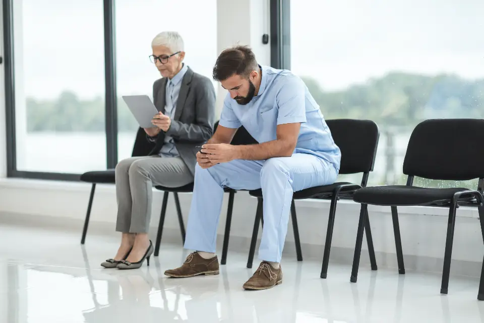 Dua orang menunggu di deretan kursi ruang tunggu klinik